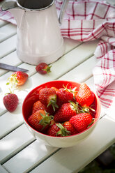 Schale mit Erdbeeren, Küchenhandtuch und Glas auf weißem Holz - LVF001246