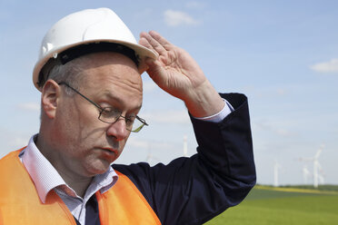 Deutschland, Techniker mit Schutzhelm vor einer Windkraftanlage - SGF000683