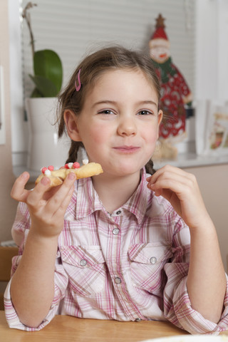 Porträt eines kleinen Mädchens, das Weihnachtsplätzchen isst, lizenzfreies Stockfoto
