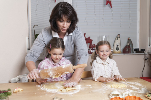 Mother with her two daughters baking Christmas cookies stock photo