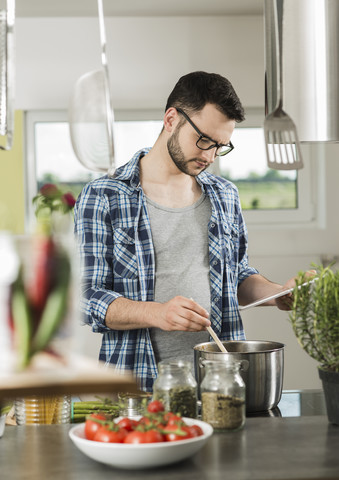 Junger Mann beim Kochen in der Küche zu Hause, lizenzfreies Stockfoto