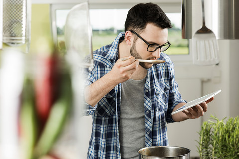 Junger Mann beim Kochen in der Küche zu Hause, lizenzfreies Stockfoto