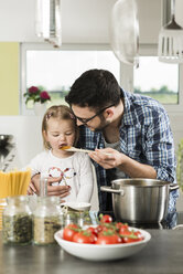 Father and daughter cooking in kitchen - UUF000496