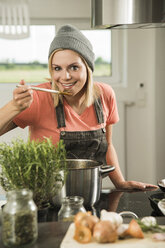 Portrait of young woman cooking in kitchen at home - UUF000491