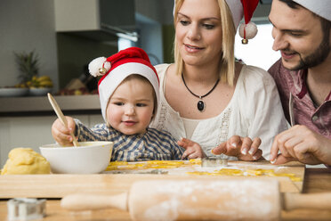 Familie mit Weihnachtsmannmützen beim Backen in der Küche - UUF000542