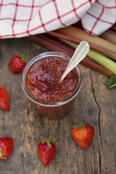 Glas Erdbeer-Rhabarber-Marmelade, Erdbeeren, Küchentuch und Rhabarber auf dunklem Holz, Blick von oben - LVF001258