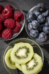 Glasschalen mit Himbeeren, Heidelbeeren und Kiwi-Scheiben auf Schiefer - SARF000608