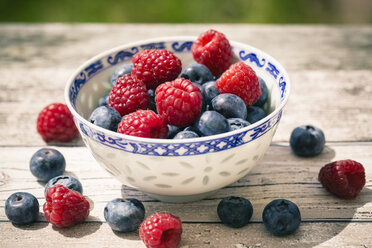 Bowl of blueberries and raspberries on wooden table - SARF000613