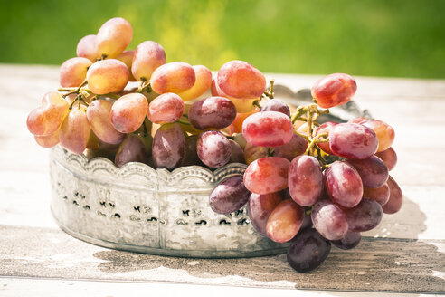 Zinc bowl of red grapes on wooden table - SARF000618