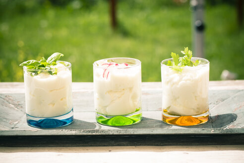 Three garnished glasses of curd with herbs on wooden tray - SARF000619