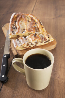 Tasse schwarzer Kaffee, Messer und Plundergebäck mit Marzipan auf Holzbrett und Tisch - CSTF000358
