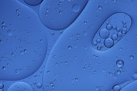 Öl und Wasser vor blauem Hintergrund, lizenzfreies Stockfoto