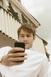 Junger Mann schaut auf sein Smartphone - MEMF000315