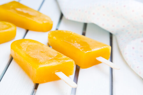 Four mango apple ice cream lollies and cloth on white wood - LVF001274