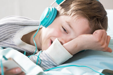 Portrait of boy with headphones lying on beanbag - LVF001284