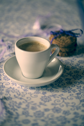 Tasse Kaffee und Schokoladenkekse auf gemustertem Tuch, lizenzfreies Stockfoto