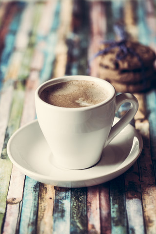 Tasse Kaffee und Schokoladenkekse auf farbigem Holz, lizenzfreies Stockfoto