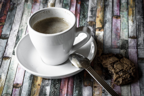 Tasse Kaffee und Schokoladenkekse auf farbigem Holz, lizenzfreies Stockfoto