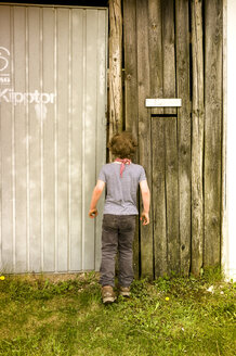 Little boy peeking through spy hole in garage - TKF000348