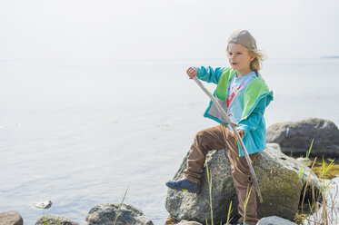 Germany, Mecklenburg-Western Pomerania, Ruegen, Boy sitting on rock at the ocean - MJF001257