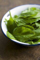 Bowl of spinach leaves, Spinacia oleracea, on wood - HAWF000185