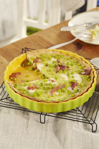 Homemade pea and ham quiche on kitchen table stock photo