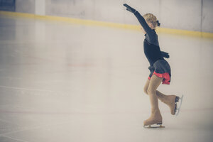 Junge Eiskunstläuferin bewegt sich bei einem Wettbewerb auf der Eisbahn - MJF001278