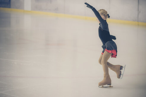 Junge Eiskunstläuferin bewegt sich bei einem Wettbewerb auf der Eisbahn - MJF001278