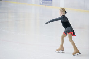 Junge Eiskunstläuferin bewegt sich bei einem Wettbewerb auf der Eisbahn - MJF001279