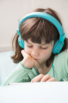 Porträt eines kleinen Mädchens mit Kopfhörern und Smartphone - LVF001306