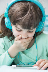 Portrait of little girl with headphones using smartphone - LVF001308