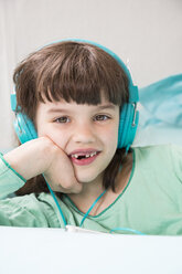 Porträt eines lachenden kleinen Mädchens mit Kopfhörern und Smartphone - LVF001309