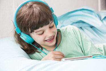 Portrait of little girl with headphones using smartphone - LVF001312