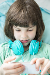 Porträt eines kleinen Mädchens mit Kopfhörern und Smartphone - LVF001314