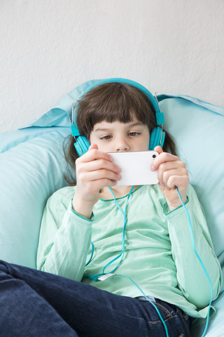 Porträt eines kleinen Mädchens mit Kopfhörern und Smartphone, lizenzfreies Stockfoto