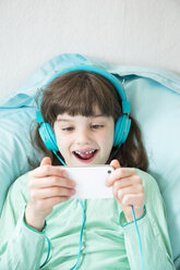 Porträt eines kleinen Mädchens mit Kopfhörern und Smartphone - LVF001317