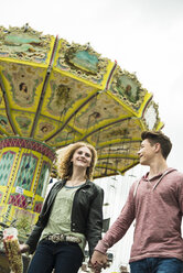 Teenage couple at fun fair with chairoplane in the background - UUF000663
