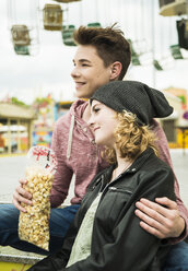 Porträt eines glücklichen Teenagerpaares mit Popcorn auf dem Jahrmarkt - UUF000659