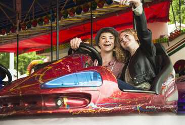 Teenage couple sitting in bumper car photographing themself with smartphone - UUF000616