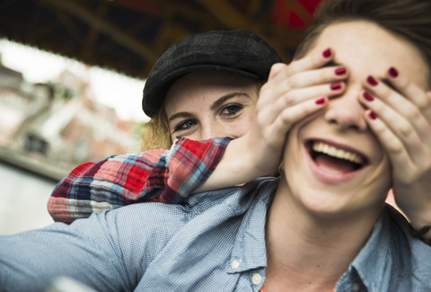 Teenager-Mädchen bedeckt die Augen ihres Freundes mit ihren Händen, lizenzfreies Stockfoto