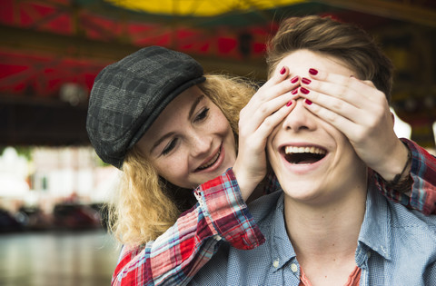 Teenager-Mädchen bedeckt die Augen ihres Freundes mit ihren Händen, lizenzfreies Stockfoto