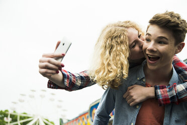 Portrait of teenage couple photographing themself at fun fair - UUF000672