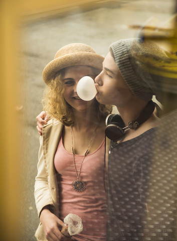 Teenage girl watching gum bubble of her boyfriend stock photo