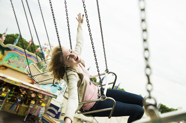 Happy eenage girl on chairoplane at fun fair - UUF000674