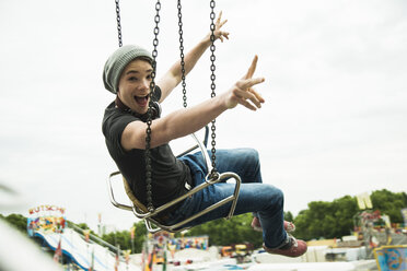 Teenage boy on chairoplane at fun fair - UUF000675