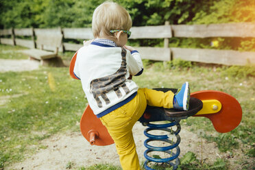 Kleinkind klettert auf Schaukeltier auf Spielplatz - MFF001113