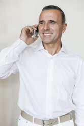 Porträt eines lächelnden Oberarztes, der mit einem Smartphone telefoniert - MFF001125
