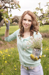 Porträt einer lächelnden Frau mit Blumentopf im Garten - VTF000230