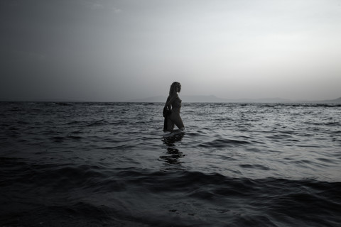 Griechenland, Korfu, nackte junge Frau beim Spaziergang im Meer, lizenzfreies Stockfoto