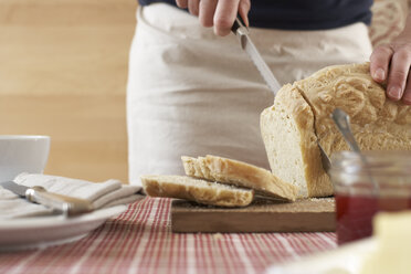Woman cutting home-made yeast bread on chopping board, partial view - SABF000020